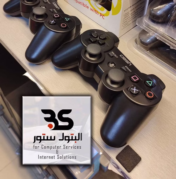 جيمبادات لاسلكية مزدوجة على رف مع شعار متجر البتول، مثالية لعشاق الألعاب وتجربة لعب Crash الرائعة. البتول ستور